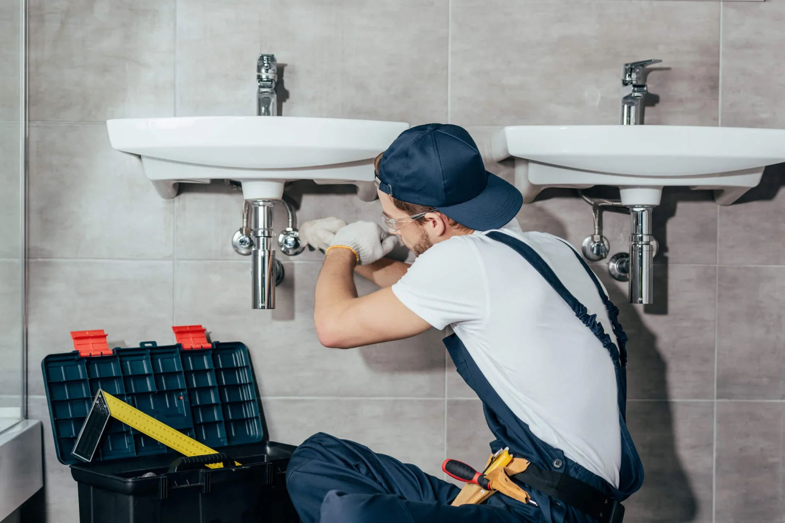 A young plumber fixing sink in bathroom